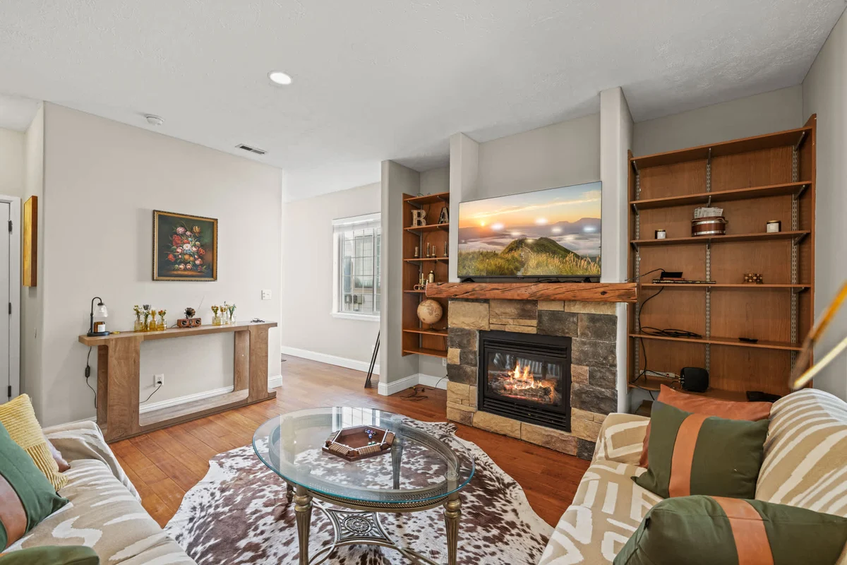 Cozy living room with stone fireplace and wood shelving at Woodland Retreat Cabin, a dog-friendly Coeur d'Alene vacation rental