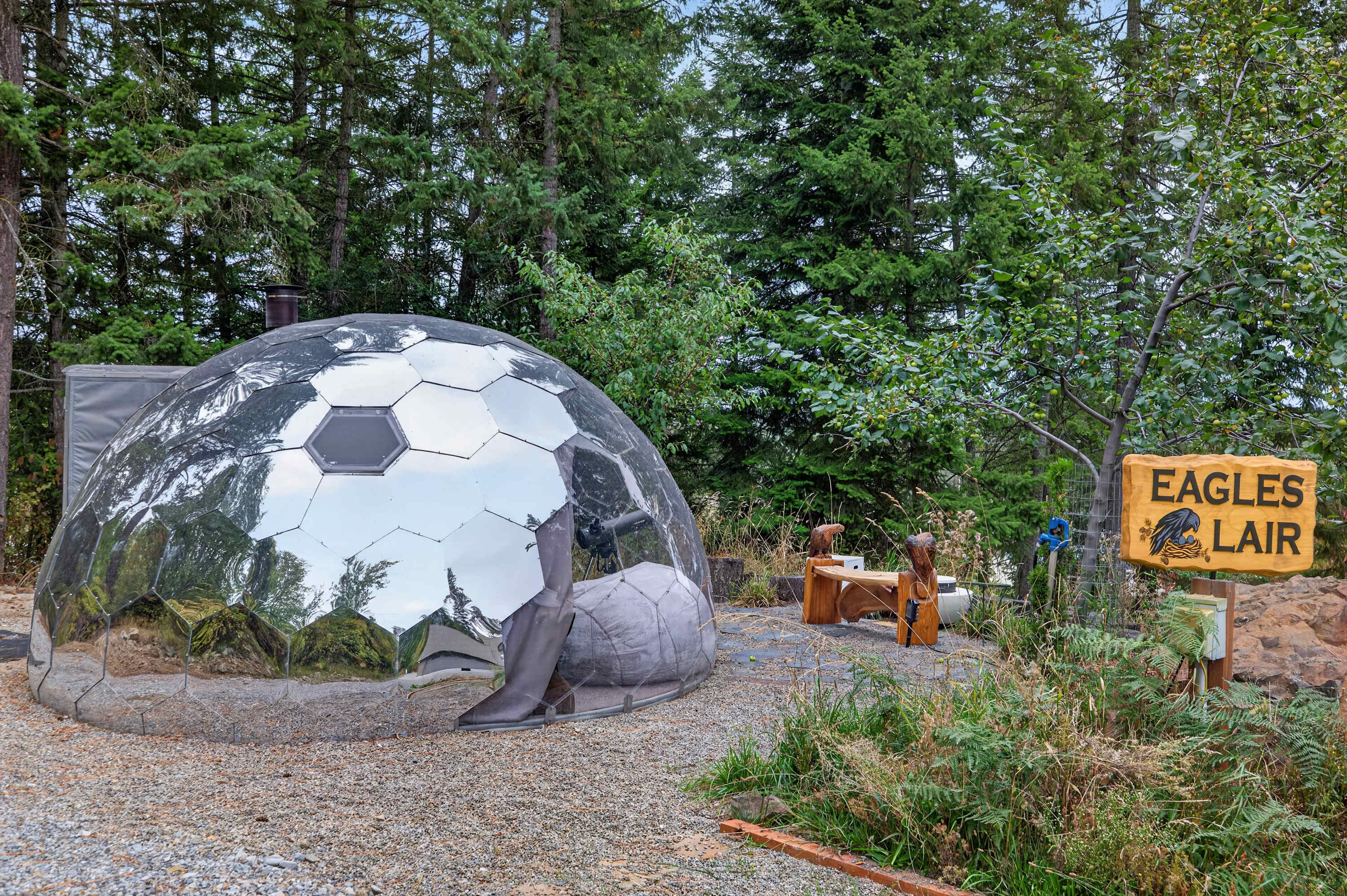 The Eagles Lair mirrored geodesic dome tucked among the pines at Eagles Nest, with the Eagles Lair sign beside it